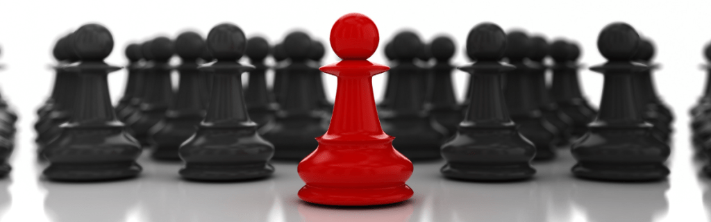 black chess pieces with one red piece in front representing leadership